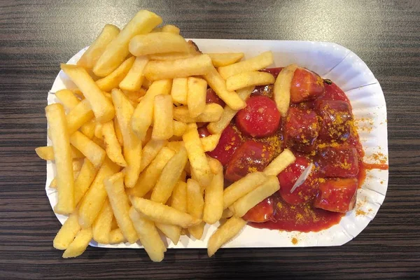 В даний-німецькому посуді з нарізаної свинячої ковбаси з кетчупом каррі і картоплею фрі — стокове фото