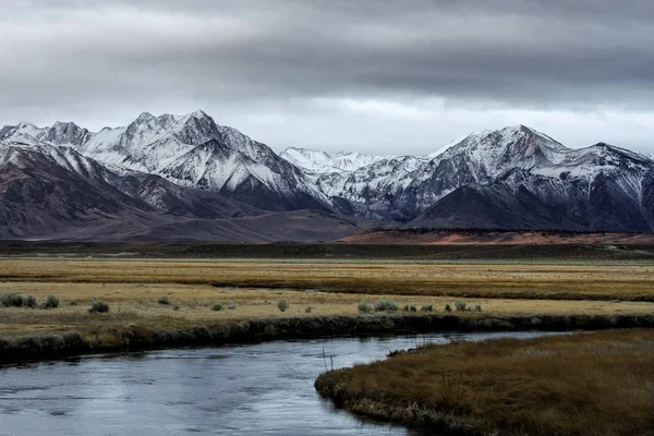 Hermosa amplia toma de montañas rodeadas por un río y campos de hierba plana — Foto de Stock