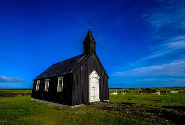 Kostel uprostřed travnatého pole pod jasnou modrou oblohou ve dne — Stock fotografie