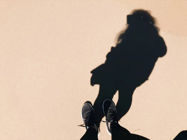 Füße eines Weibchens mit ihrem Schatten auf hellrosa Hintergrund — Stockfoto