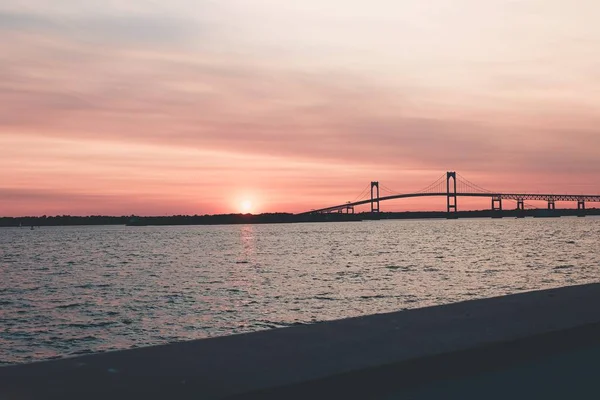 Belo tiro de paisagem de uma ponte perto do mar abaixo do céu rosa — Fotografia de Stock