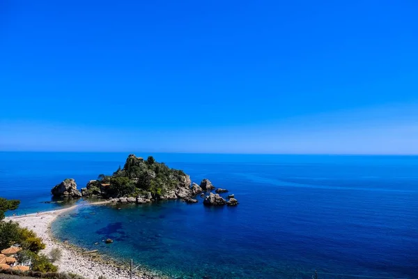 Fotografia aérea de rochas musgosas perto do mar com céu azul claro no fundo — Fotografia de Stock