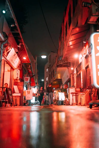 Tiro de pessoas andando ao longo de uma rua estreita perto de cafés e lojas durante a noite no Japão — Fotografia de Stock