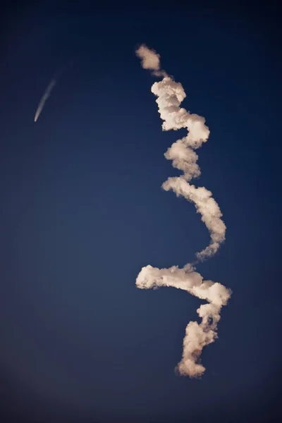 Vertikalt skott av vita spår kvar efter ett flygplan i en klarblå himmel — Stockfoto