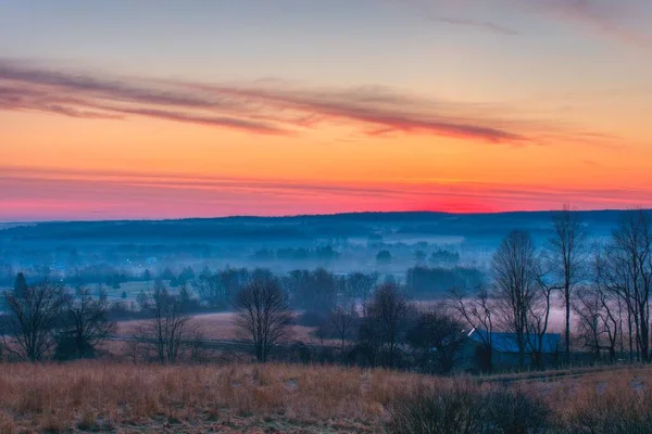 Belo tiro de incríveis nuvens vermelhas e laranja sobre grandes campos nebulosos e floresta ao amanhecer — Fotografia de Stock