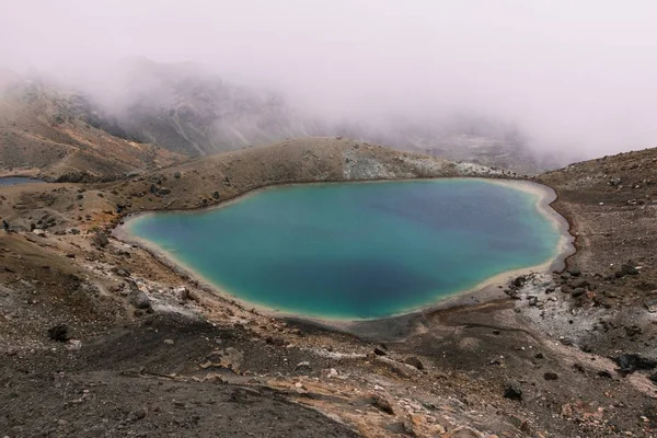 Piękne zdjęcie z powietrza małego jeziora na środku pustyni w pobliżu góry w mglisty dzień — Zdjęcie stockowe