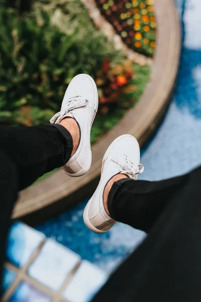 Los pies de la persona sobre un hermoso jardín una piscina en un desenfoque en el fondo — Foto de Stock