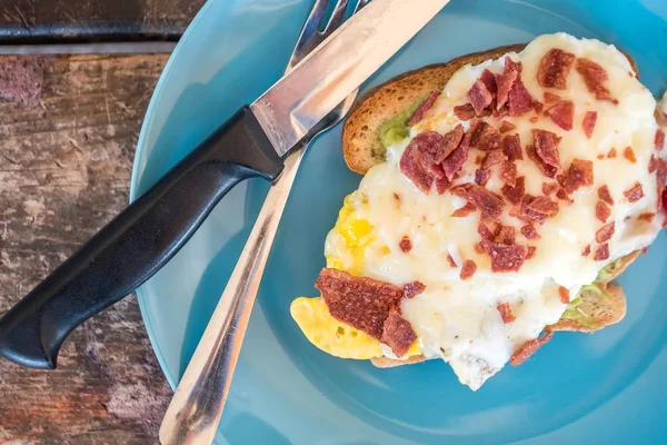 Gros plan d'un délicieux sandwich aux œufs avec des saucisses coupées sur une assiette bleue — Photo