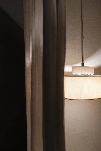 Uma lâmpada de teto ao lado de uma cortina — Fotografia de Stock