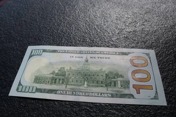 Gros plan d'un billet de cent dollars sur un ciment gris foncé — Photo