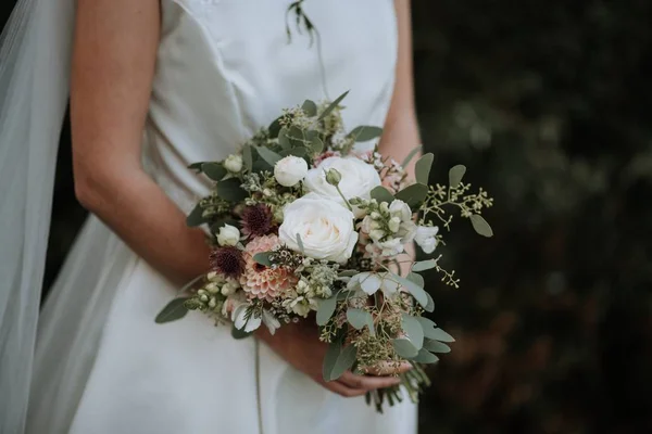 Bel colpo di una sposa che indossa abito da sposa in possesso di un mazzo di fiori — Foto Stock