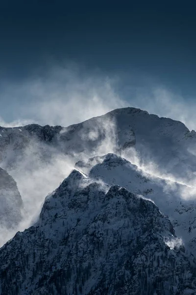 Красивые высокие снежные и туманные горы со снегом, развевающимся ветром — стоковое фото