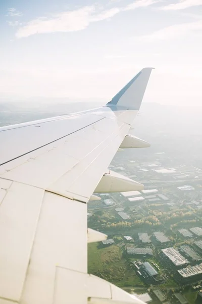 A wing of a large commercial aircraft flying over a city in the US