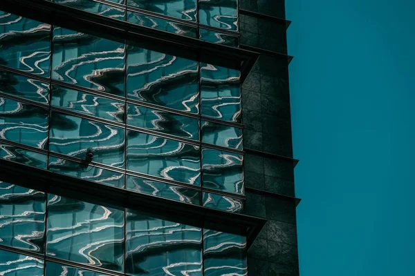 Fechar tiro de um edifício de vidro com uma câmera de segurança e um céu azul no fundo — Fotografia de Stock