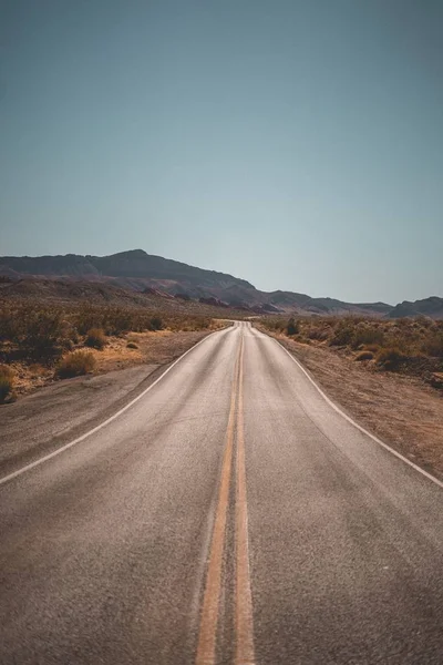 Порожня вузька пустельна дорога з красивими пагорбами на задньому плані — стокове фото