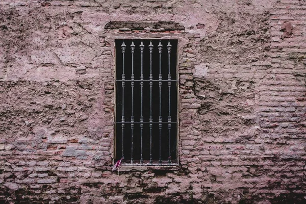 Primer plano de una vieja pared de ladrillo envejecido con una ventana de metal con pinchos que lo cubre —  Fotos de Stock