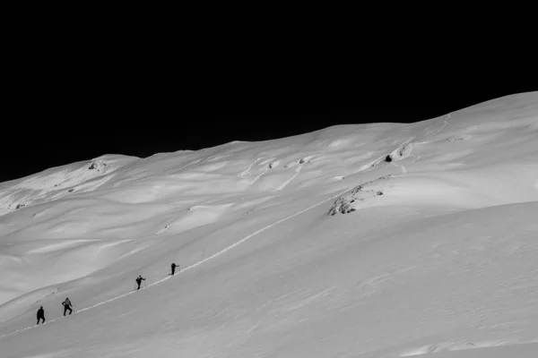 Escursionisti che camminano su una ripida collina innevata di notte — Foto Stock