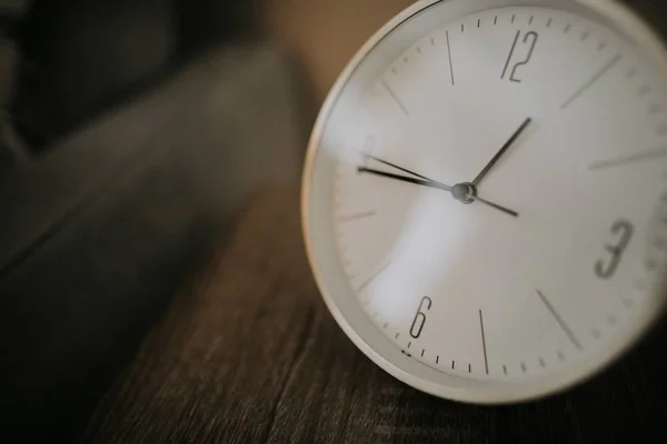 Nahaufnahme einer weißen Uhr auf einer hölzernen braunen Oberfläche — Stockfoto