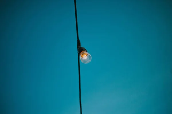 파란색 배경 이 있는 검은 수직선 줄 위에 전구를 켜 놓은 모습 — 스톡 사진