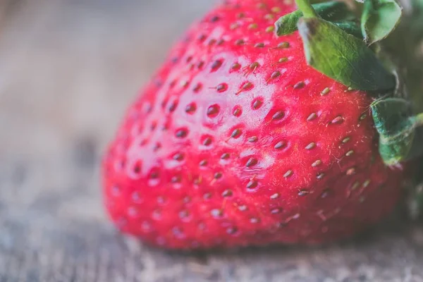 Nahaufnahme frischer reifer Erdbeeren auf einem unscharfen hölzernen Hintergrund — Stockfoto