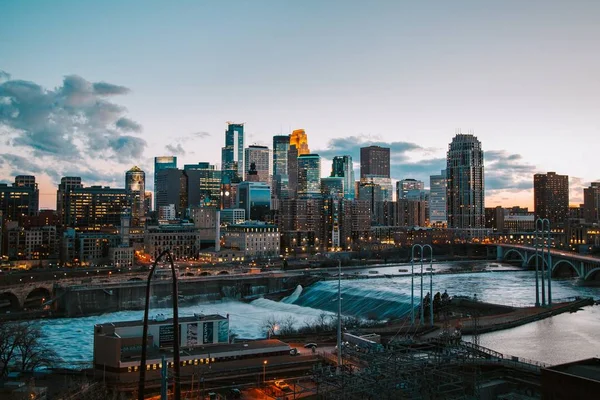 Bred bild av ett stadsområde med höga byggnader, vattenfall och bro — Stockfoto