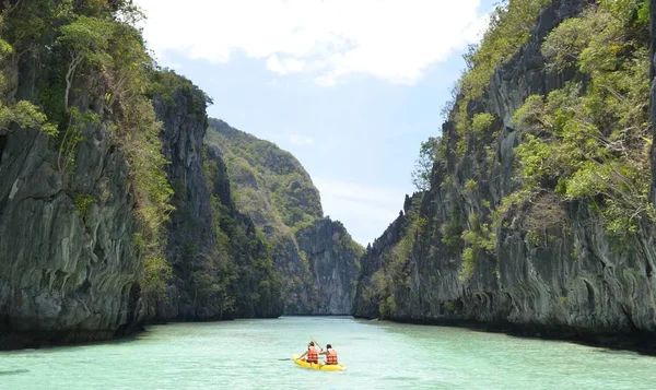 Wide shot of two males rowing a boat in life vests on beautiful El Nido island in the Philippines — 스톡 사진