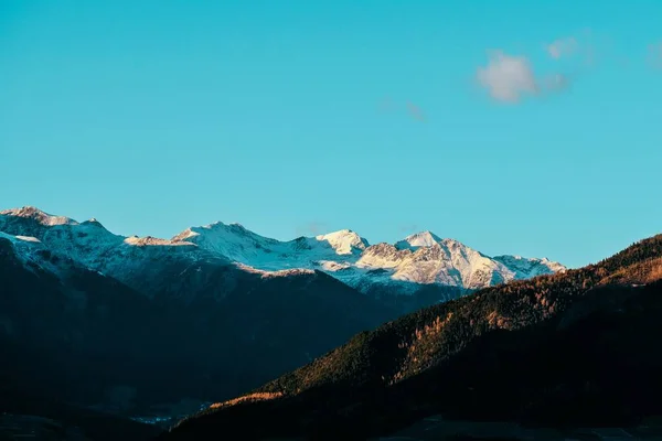 Piękne Ujęcie Zalesionych Wzgórz Śnieżnej Góry Oddali Błękitnym Niebem Tle — Zdjęcie stockowe