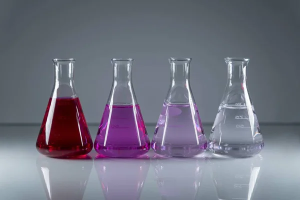 Kolby chemiczne w rzędzie z różnymi kolorami niebezpiecznego toksycznego płynu w nich — Zdjęcie stockowe