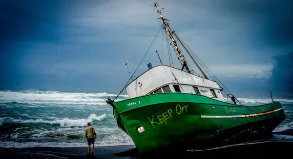 Заброшенное судно на пляже под названием "Верна" с предупреждающими знаками — стоковое фото