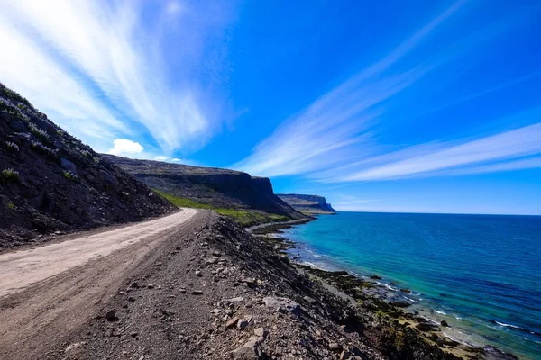 Dirt road in the middle of the hills near the sea under a blue sky