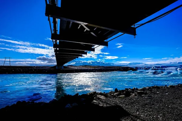 Широкий знімок крижаного моря з крижаними шкаралупами і кубиками під чорним мостом — стокове фото
