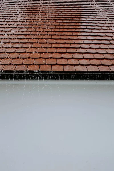 Vertikale Aufnahme von nassen Dachziegeln mit Wasser, das bei Regen nach unten fließt — Stockfoto