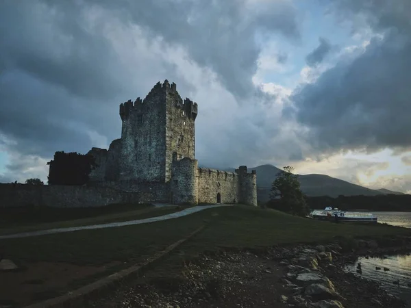 A beautiful shot of the ross castle near the sea with a cloudy background