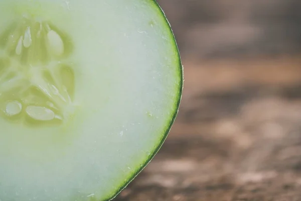 Closeup shot of sliced cucumber on a blurred wooden background — Stock Photo, Image