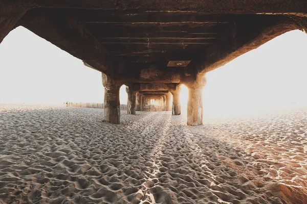 Debajo del puente de madera en la playa de arena —  Fotos de Stock