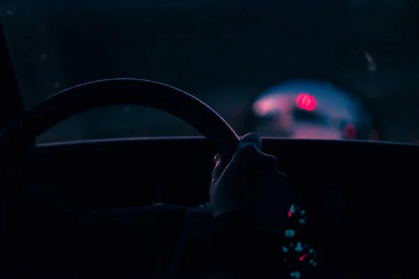 Closeup shot of a person's hand on a wheel driving a car with a blurred background — Stock Photo, Image