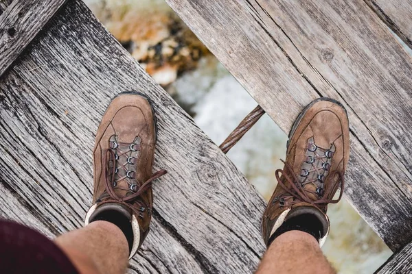 Overhead shot of a male feet standing on a wooden bridge wearing hiking shoes