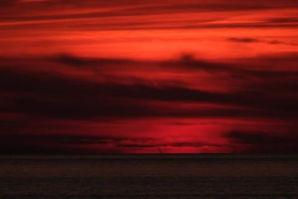 Cielo rojo y nubes sobre el mar — Foto de Stock