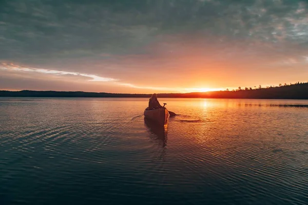 Gambar jauh yang indah dari seorang perempuan mengendarai kayak di tengah danau saat matahari terbenam — Stok Foto