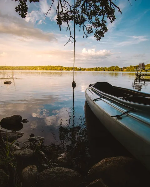 Potret vertikal perahu di danau yang dikelilingi oleh tanaman dan batu — Stok Foto