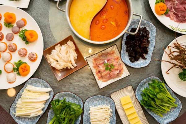 High angle shot of soup near a plate with raw meat with a side dishes — Stock Photo, Image