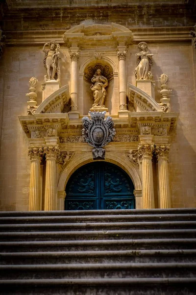 Vertical shot of stairs leading up to a sculpted doorway with a blue door
