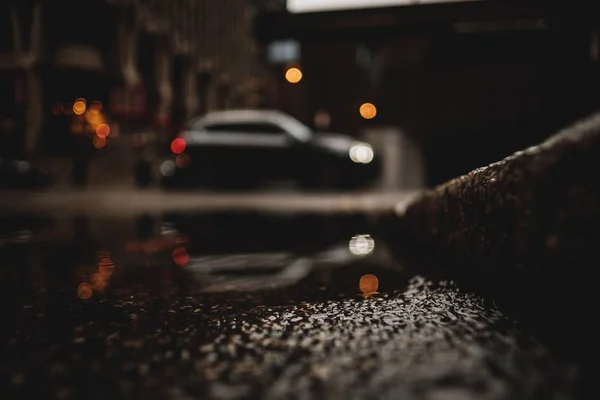 Un plan d'angle bas d'une voiture avec réflexion dans la flaque d'eau — Photo