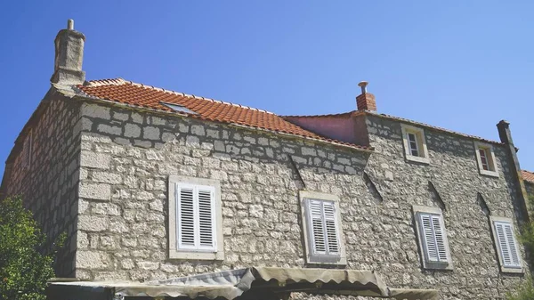 Vue rapprochée d'une maison en brique avec fenêtres blanches et bardeaux de toit orange — Photo