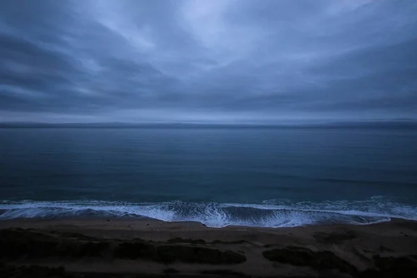 Красивый Снимок Пляжа Тёмными Облаками Спокойной Водой Туманную Погоду — стоковое фото