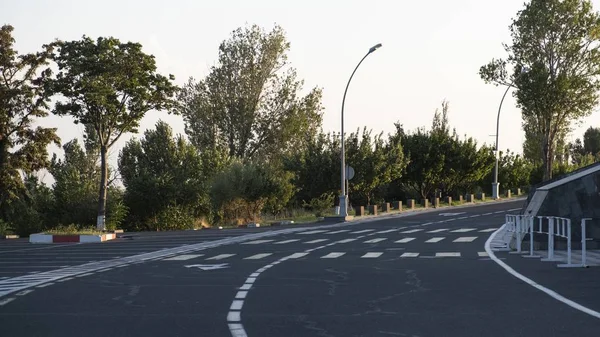 Zakrzywiona droga z białymi liniami drogowymi i symbolami otoczonymi zielenią w Armenii — Zdjęcie stockowe