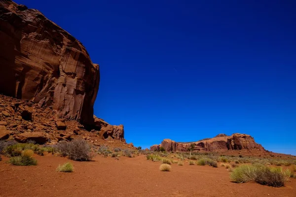 Deserto con cespugli secchi e scogliere con cielo azzurro chiaro sullo sfondo — Foto Stock