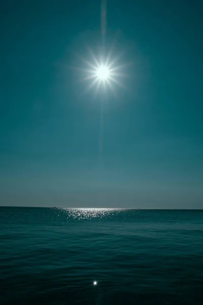 Vertikální záběr moře odrážející slunce s jasně modrou oblohou — Stock fotografie