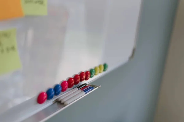 Closeup shot a tábla színes csapok és három markerek a tálcán polc — Stock Fotó