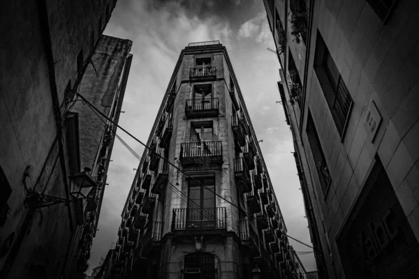 Balança em tons de cinza de baixo ângulo de um edifício alto com janelas longas com varandas — Fotografia de Stock